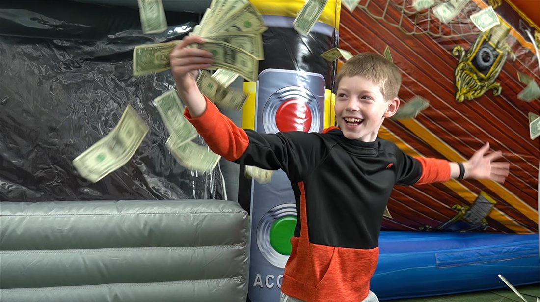A kid grabbing flying cash in the Cash Chamber at Bounce Empire